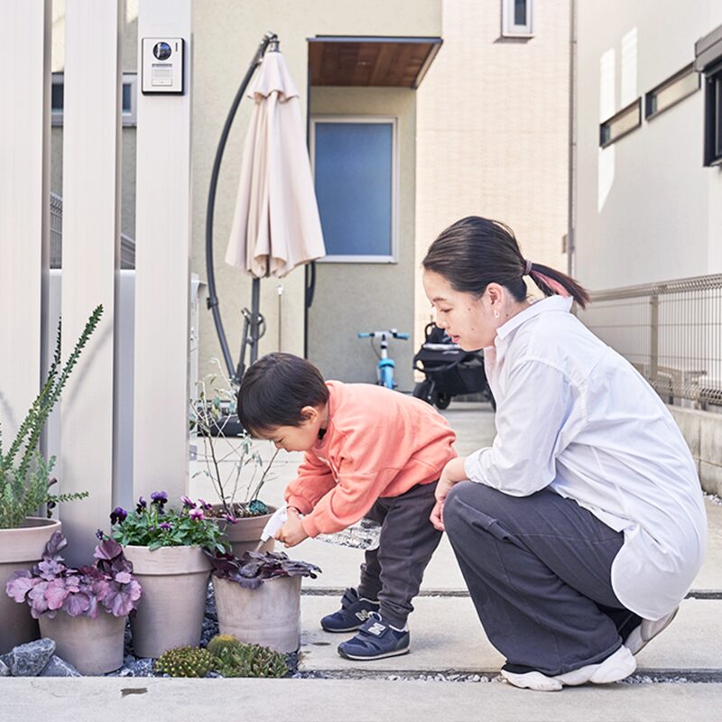 YKK APのクリアネットと庭で作業する母子の写真。